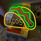 Neon sign shaped like a taco with 'TACOS' text on a soft surface.
