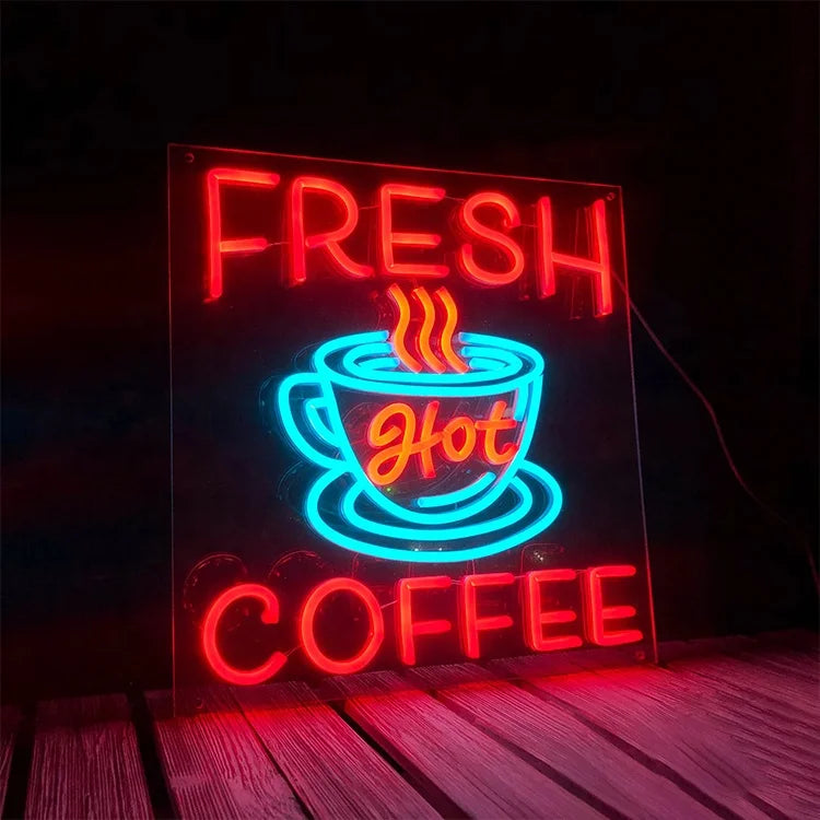 Neon sign with 'Fresh Hot Coffee' text and a coffee cup graphic on a dark background.