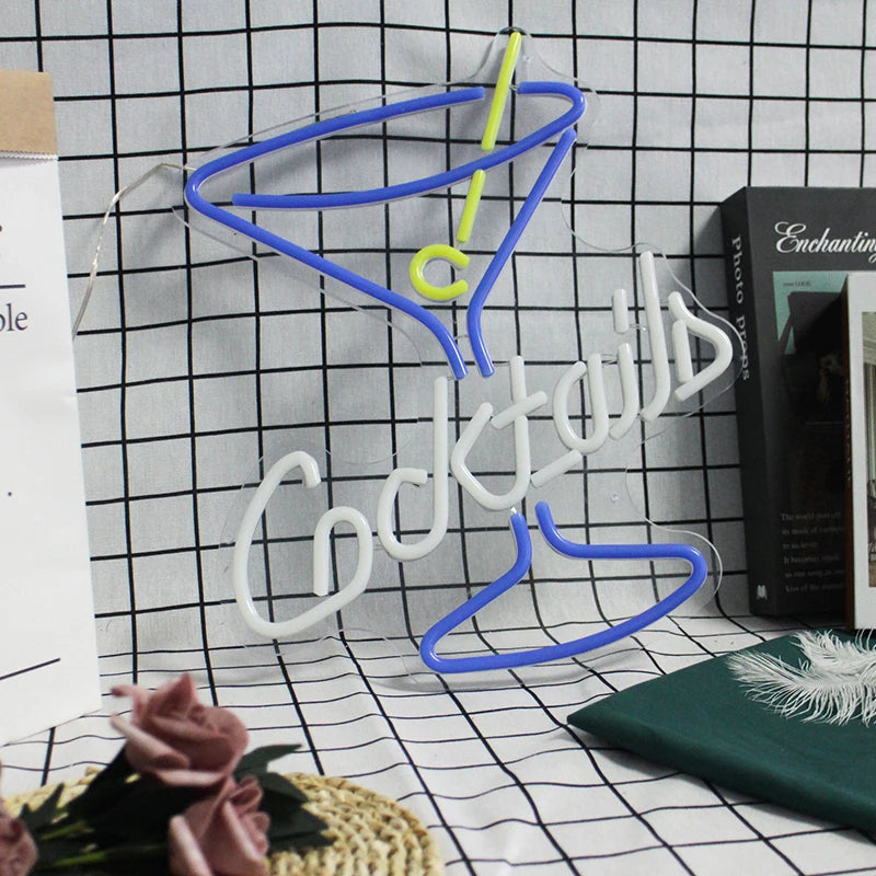 Neon sign shaped like a cocktail glass with 'Cocktails' text on a grid background
