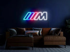 Neon sign with a logo on a dark wall above a brown sofa.