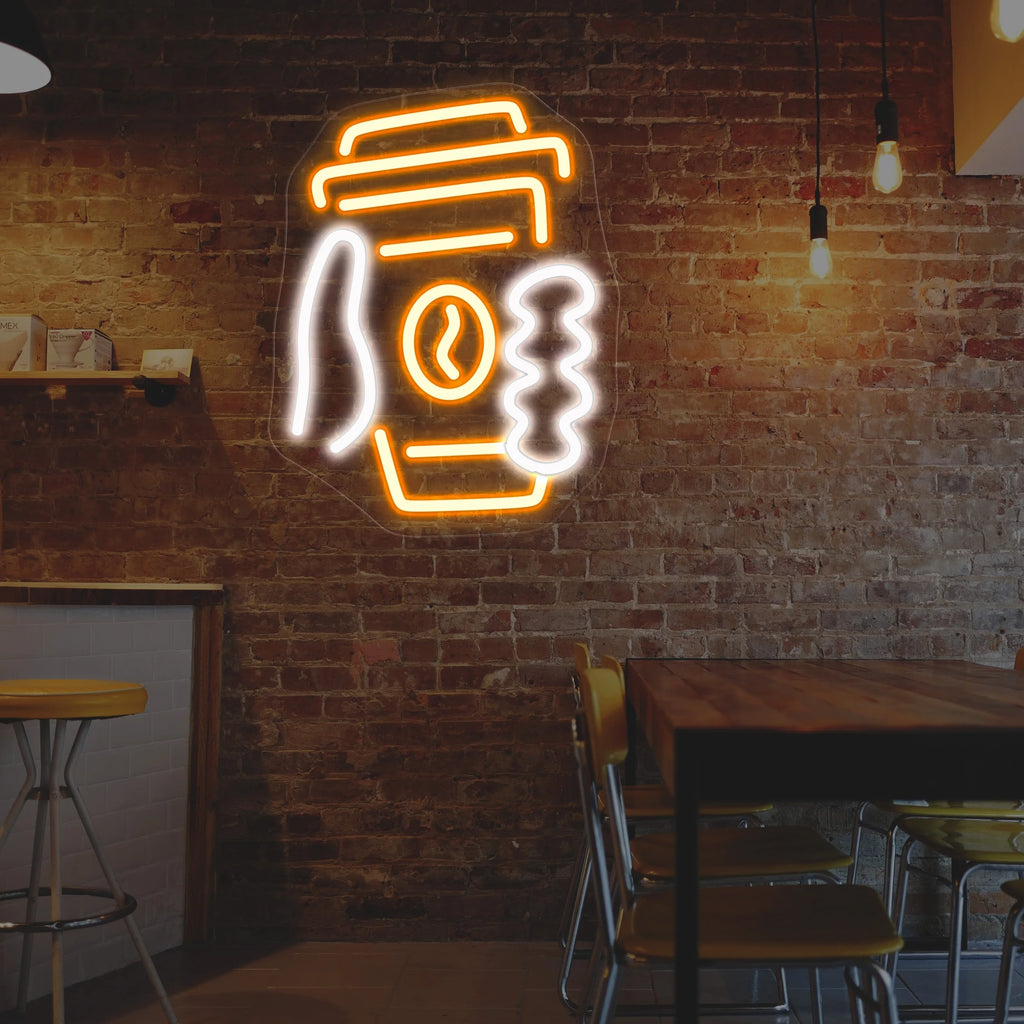 Neon sign of a coffee cup on a brick wall in a cozy cafe setting.