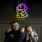 Two people sitting together with a neon sign of a duck wearing headphones above them.