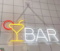 Neon sign with a cocktail glass and 'BAR' text on a tiled wall.
