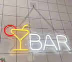 Neon sign with a cocktail glass and 'BAR' text on a tiled wall.