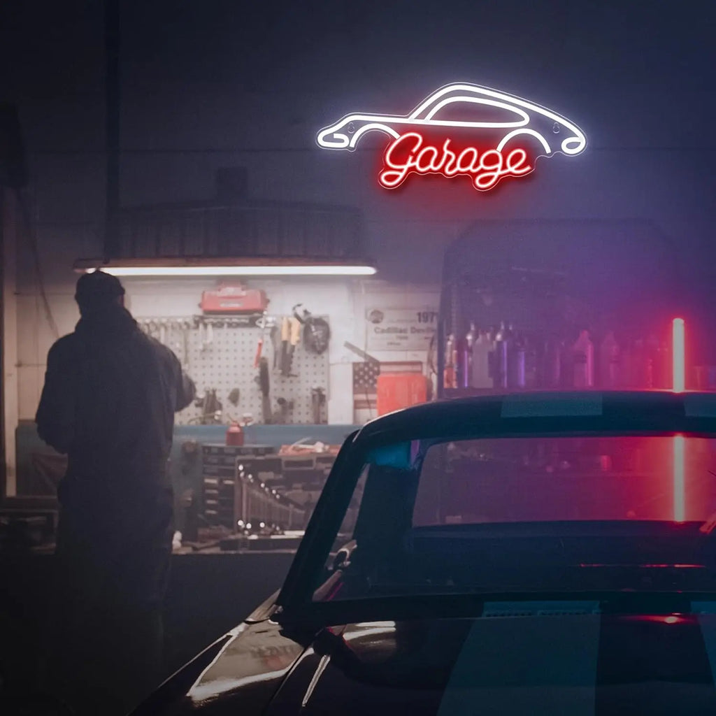 Neon 'Garage' sign above a car workshop with a person standing inside.