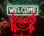 Neon sign with a crab design and 'WELCOME' text, surrounded by plants and flowers.