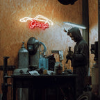 Person working in a garage with a neon 'Garage' sign on the wall.