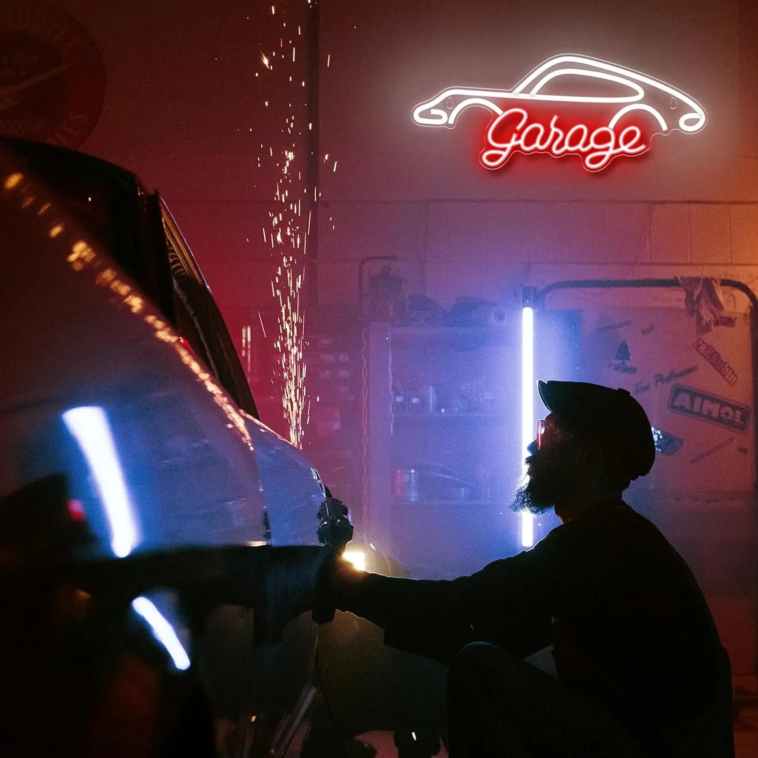 Person working on a car in a garage with a neon 'Garage' sign.