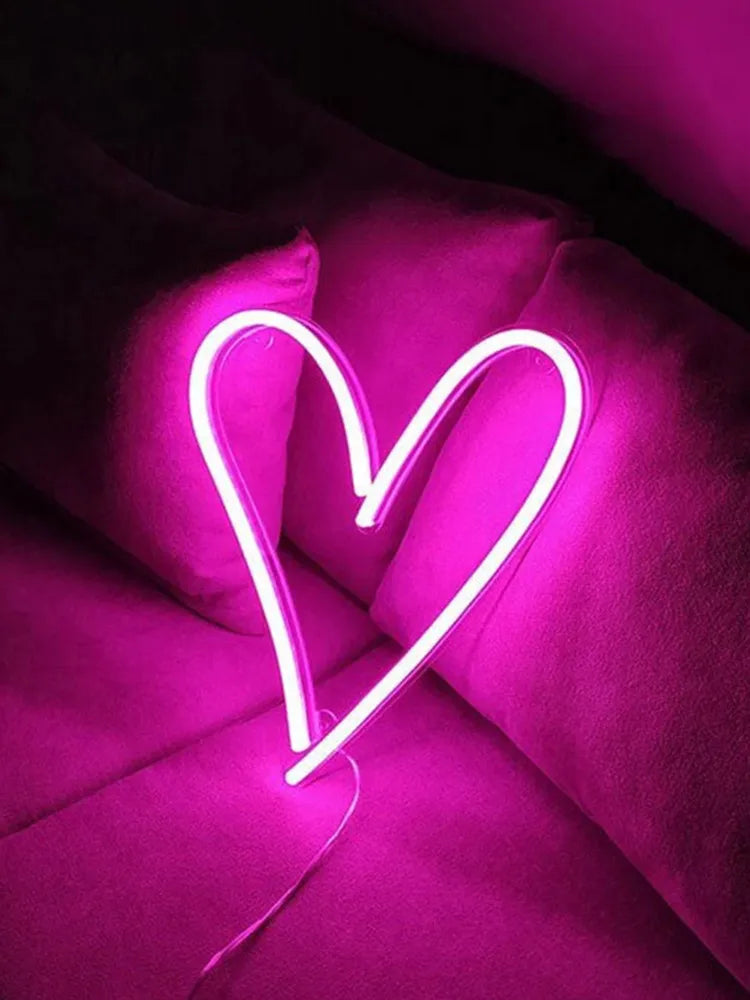 Neon heart-shaped light on a pink background