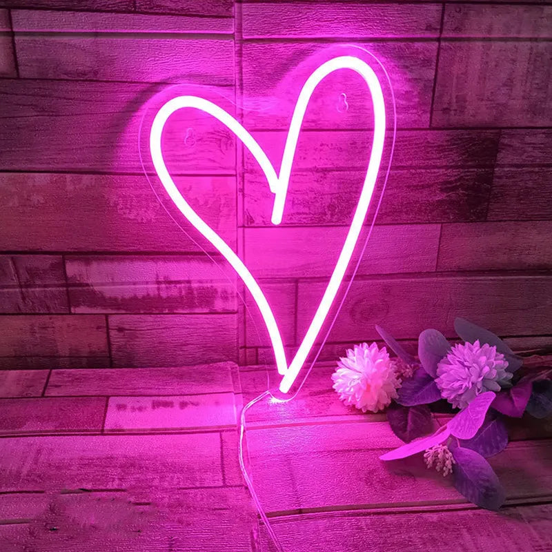 Neon heart-shaped light on a wooden surface with flowers
