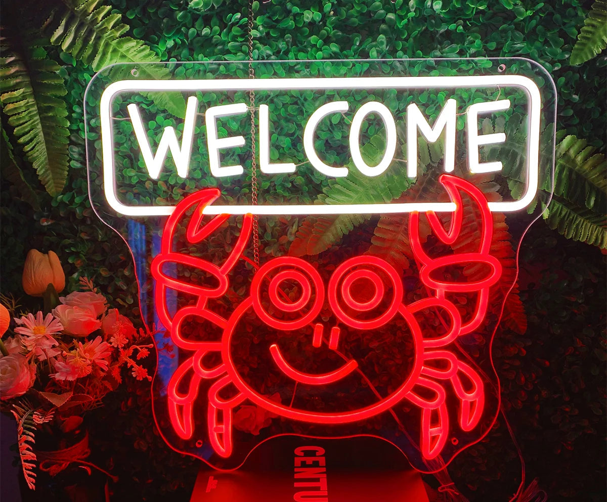 Neon sign with a crab design and 'WELCOME' text, surrounded by greenery.